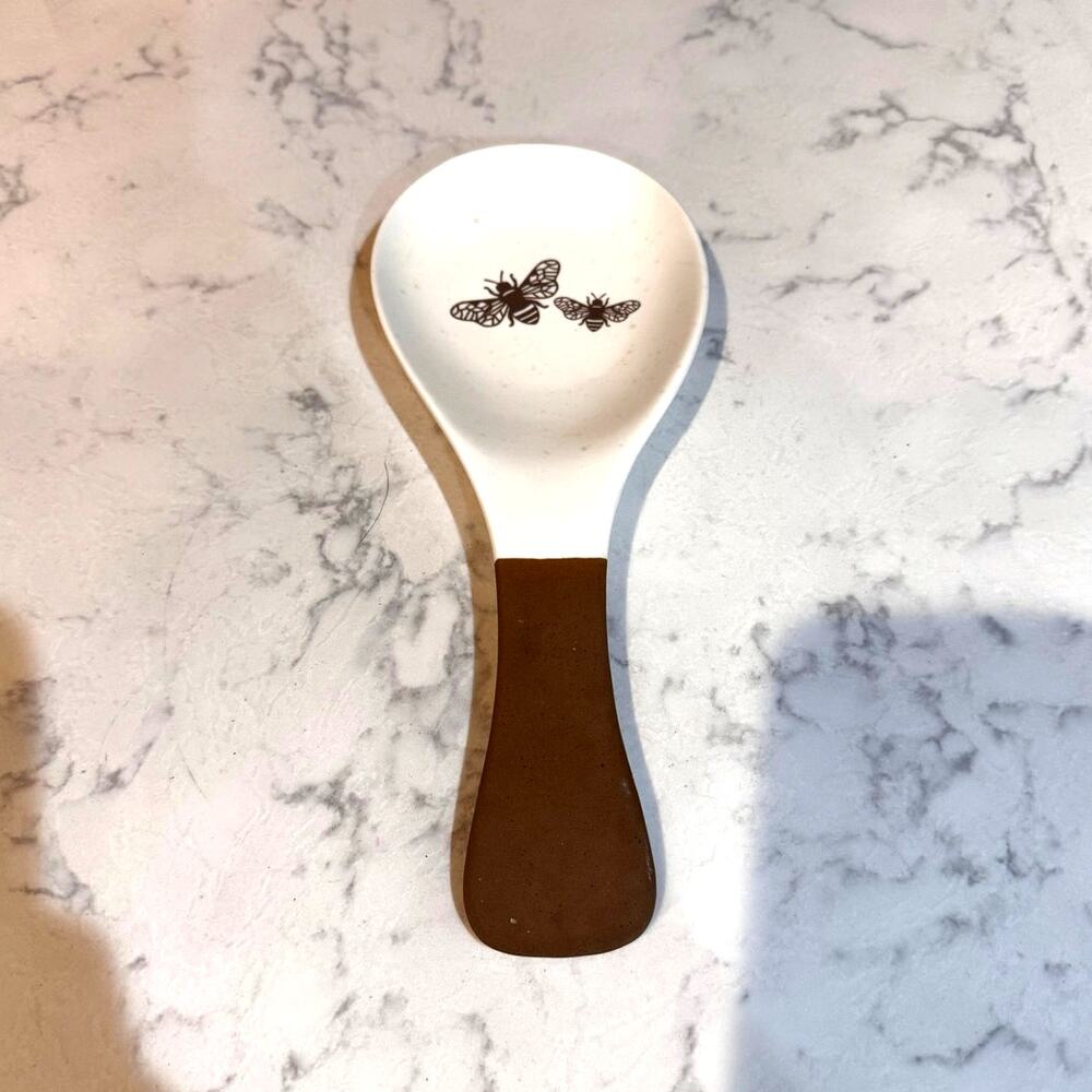 white ceramic spoon rest black bee graphic contrasting brown dipped handle